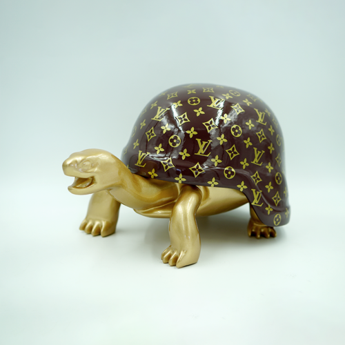 Gold tortoise figurine with a shell featuring a pattern similar to the Louis Vuitton monogram.