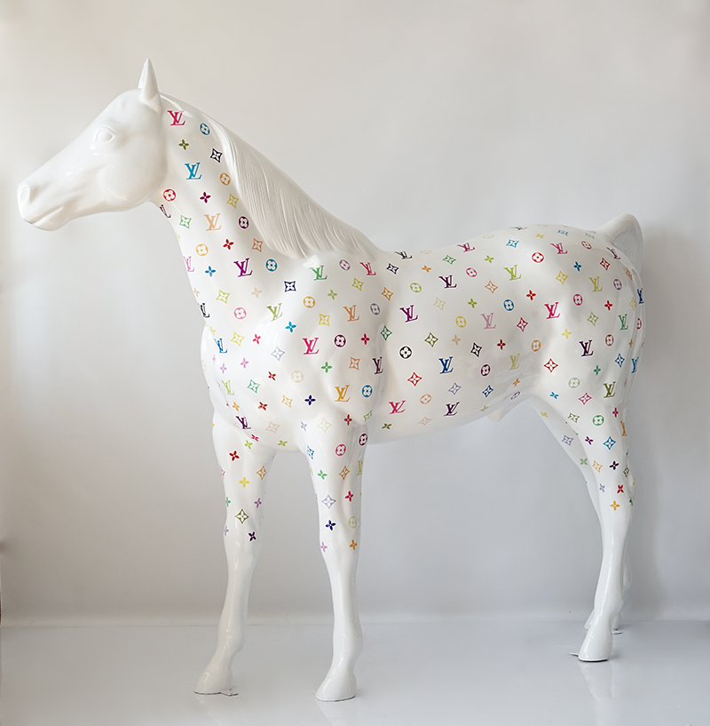 Full-size Horse - Monogram 1 A white horse statue covered in colorful Louis Vuitton logos.