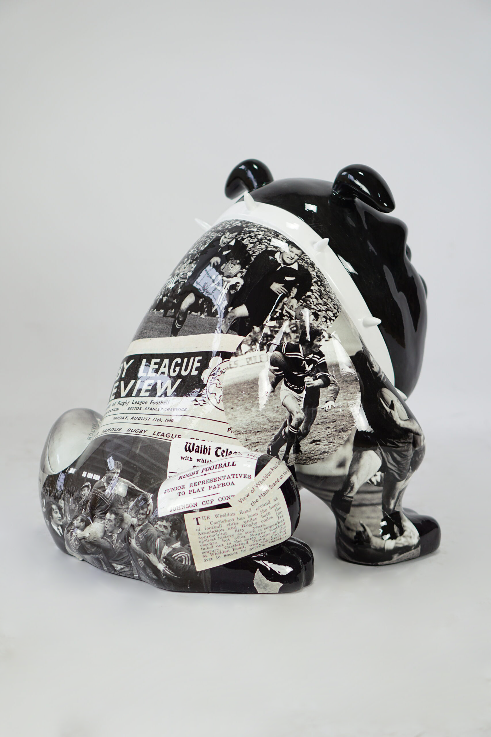 Bulldog Avella Dog 55cm - rugby 4 A sculpted figure of a black and white bulldog covered in vintage sports newspaper clippings and images of rugby players in action.