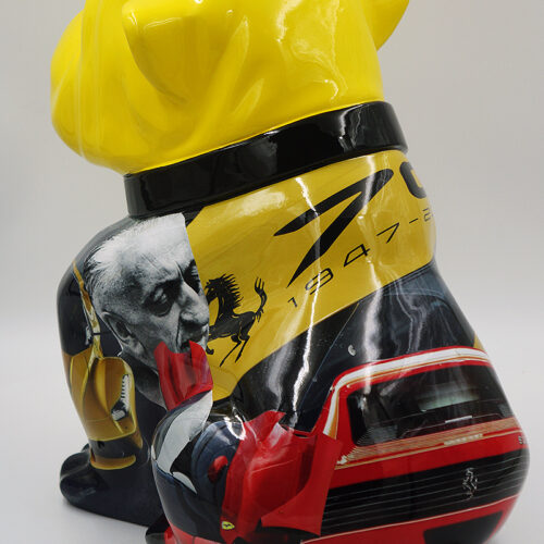 Yellow sculpture of a dog, featuring Ferrari-themed imagery, including a photo of a man, the Ferrari logo, and images of Ferrari cars.