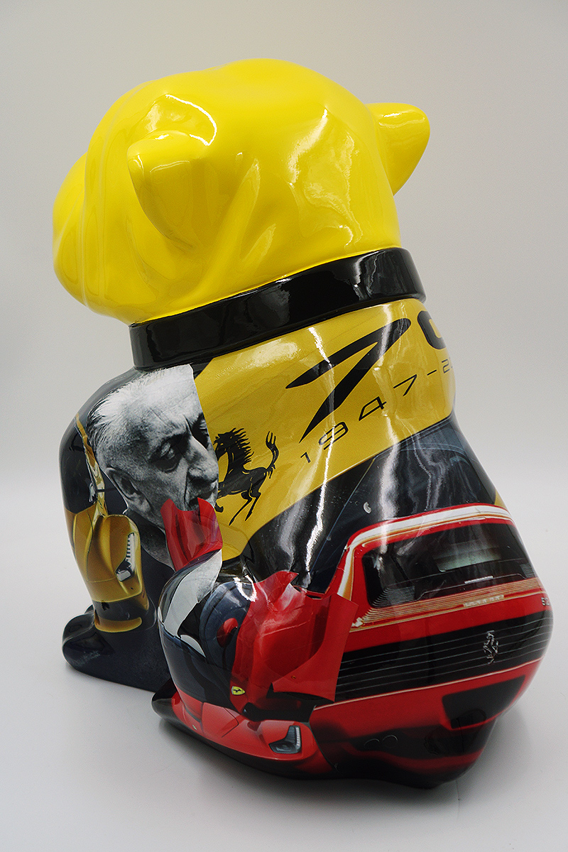 Bulldog Angelo 60cm dog - Ferrari 2 Yellow sculpture of a dog, featuring Ferrari-themed imagery, including a photo of a man, the Ferrari logo, and images of Ferrari cars.