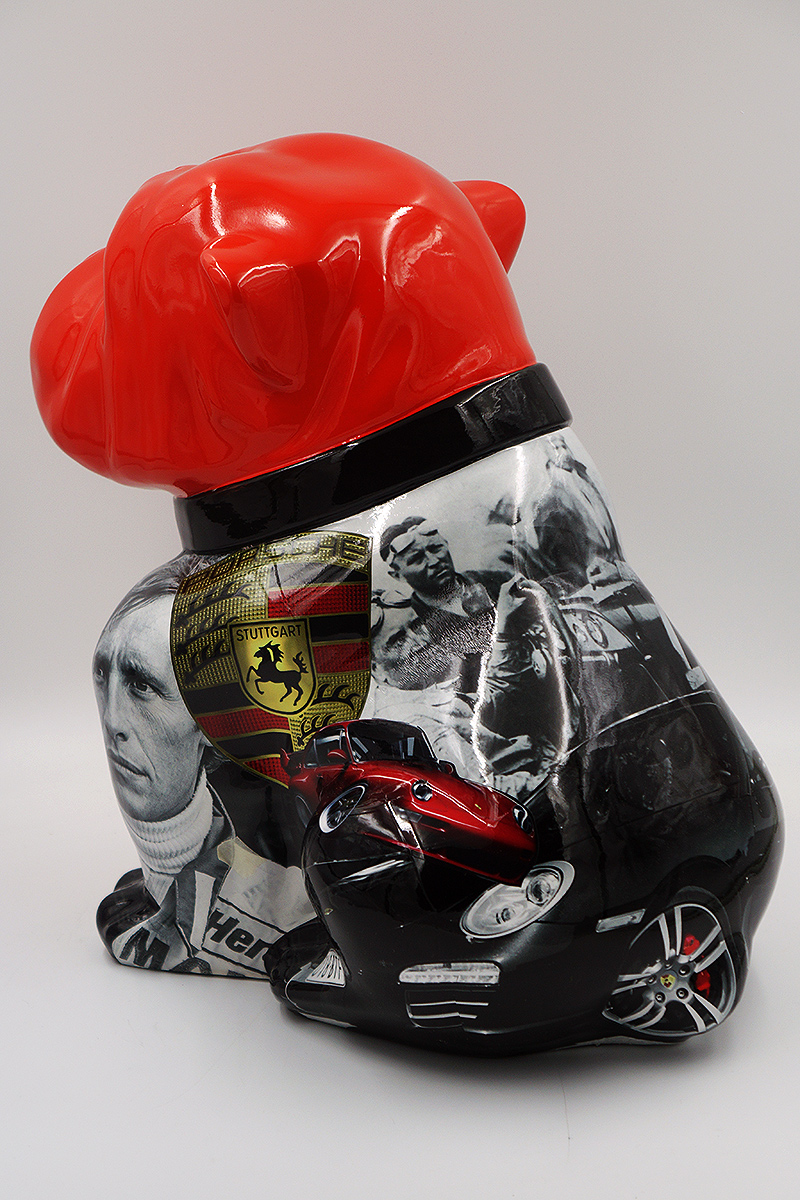 Bulldog Angelo 60cm dog - Porsche 2 Sculpture of a dog with a glossy red head and black-and-white body decorated with images of race cars, a Stuttgart emblem, and people.