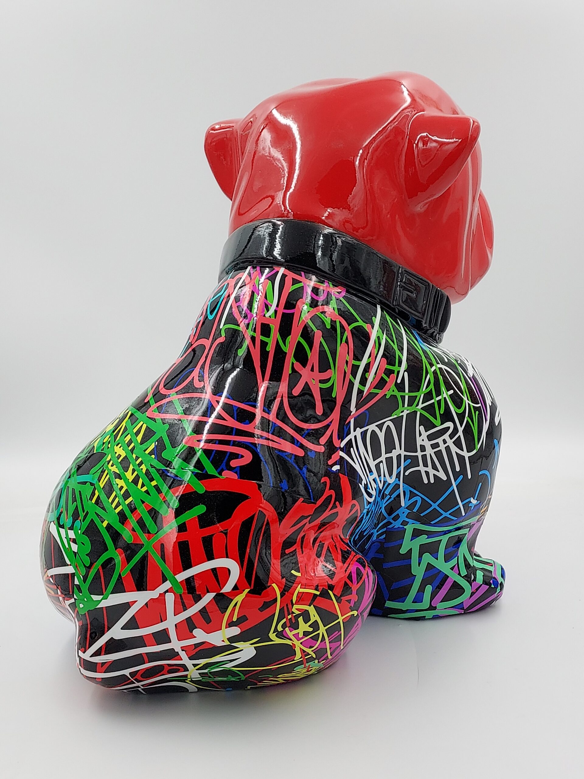 Bulldog Angelo 60cm dog - spray 2 A colorful, graffiti-covered bulldog statue with a glossy red head and black body adorned with vibrant, multicolored scribbles and tags.