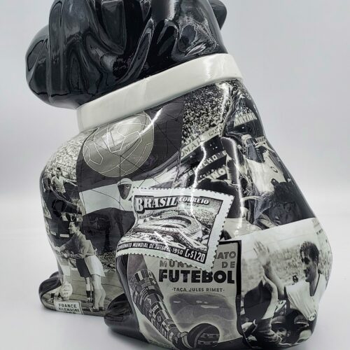Black ceramic bulldog sculpture decorated with vintage soccer-related images and memorabilia in grayscale.