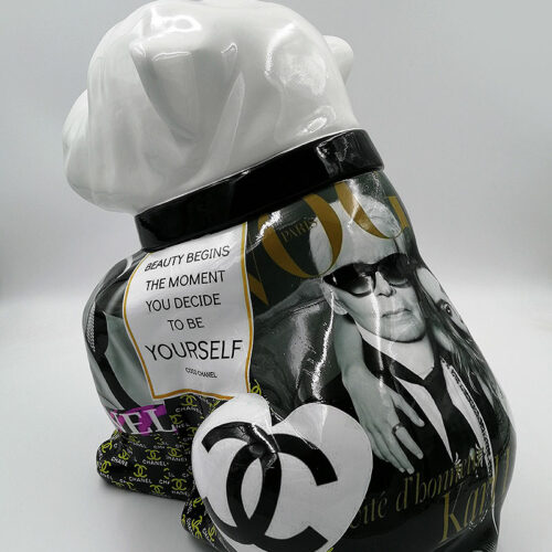 Ceramic sculpture of a bulldog with a glossy white head and black body featuring various images, Chanel logos, and a quote from Coco Chanel reading 