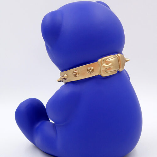 Blue bear figurine wearing a gold spiked collar, viewed from the back.