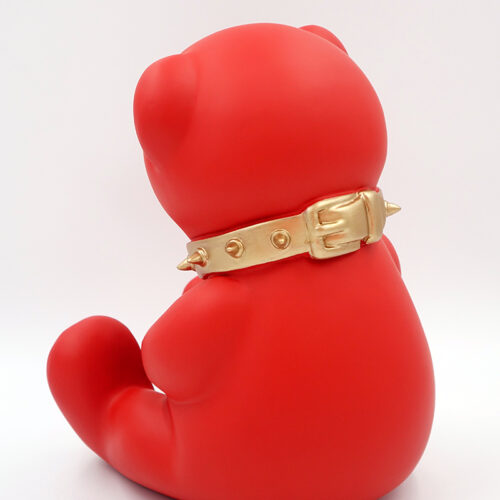 Red teddy bear figure wearing a gold spiked collar, viewed from the back.