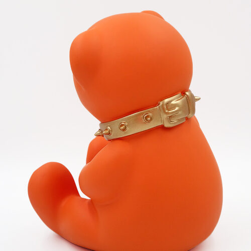 Orange bear figurine sitting with a gold spiked collar.