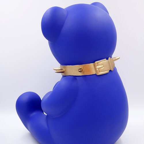 Blue sitting bear sculpture with a gold collar featuring spikes and a buckle.