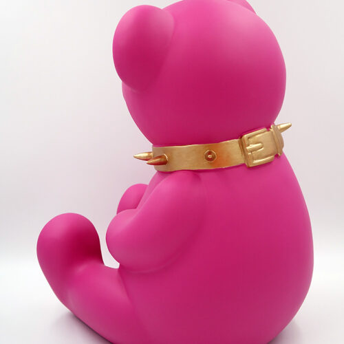 Pink bear figurine with a golden spiked collar sitting against a white background.