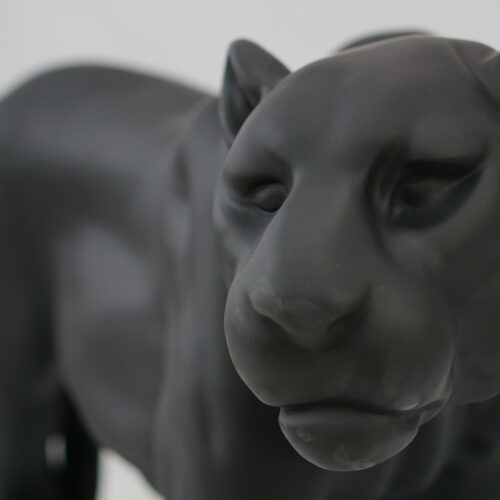 Close-up of a black panther sculpture with a smooth matte finish.
