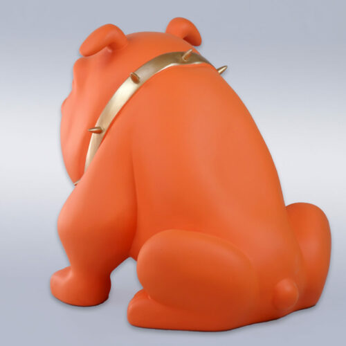 Orange bulldog sculpture with a gold spiked collar, facing away against a neutral background.