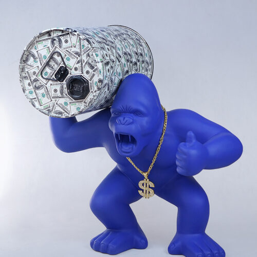 Blue gorilla statue with an open mouth, wearing a gold dollar sign necklace, posing with a large money-patterned barrel on its shoulder and giving a thumbs-up.