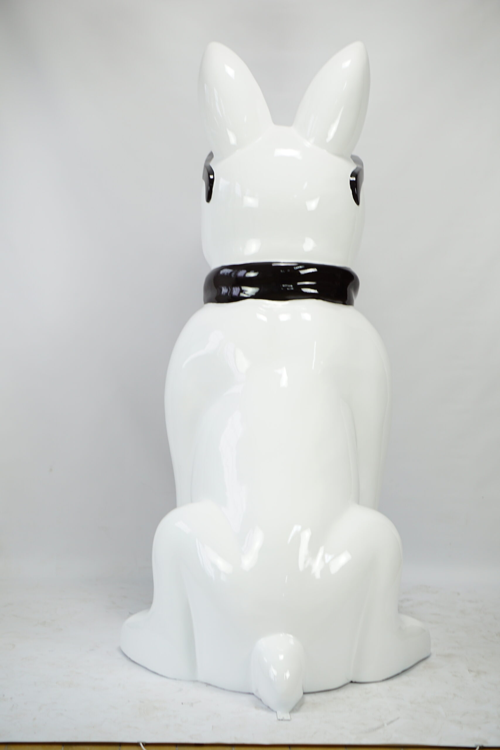 Large bulldog figure with tie and glasses - black and white 3 White ceramic sculpture of a bunny with a black collar, viewed from behind.