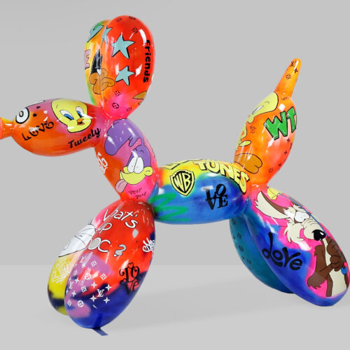 A colorful balloon dog sculpture featuring various Looney Tunes characters and graffiti-style text and illustrations.