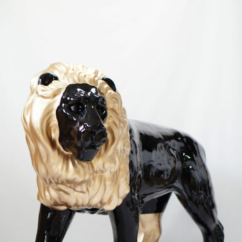 Glossy black and beige lion sculpture with a mane, placed against a plain white background.
