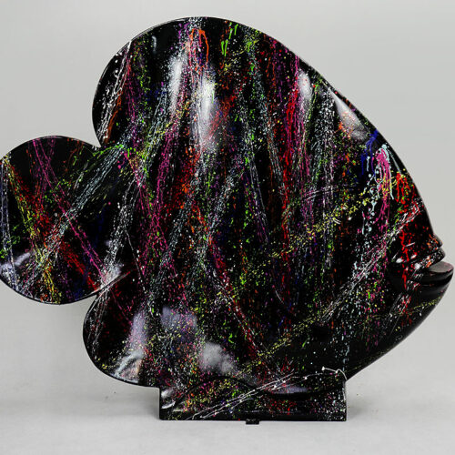 Abstract fish-shaped sculpture with a glossy black surface, splattered with vibrant colored paint in red, yellow, purple, green, and white.