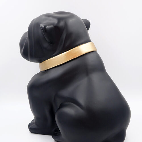Black bulldog figurine wearing a gold collar, facing away.