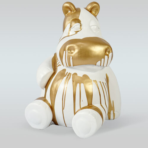 White ceramic hippo figure with gold paint dripped over it.