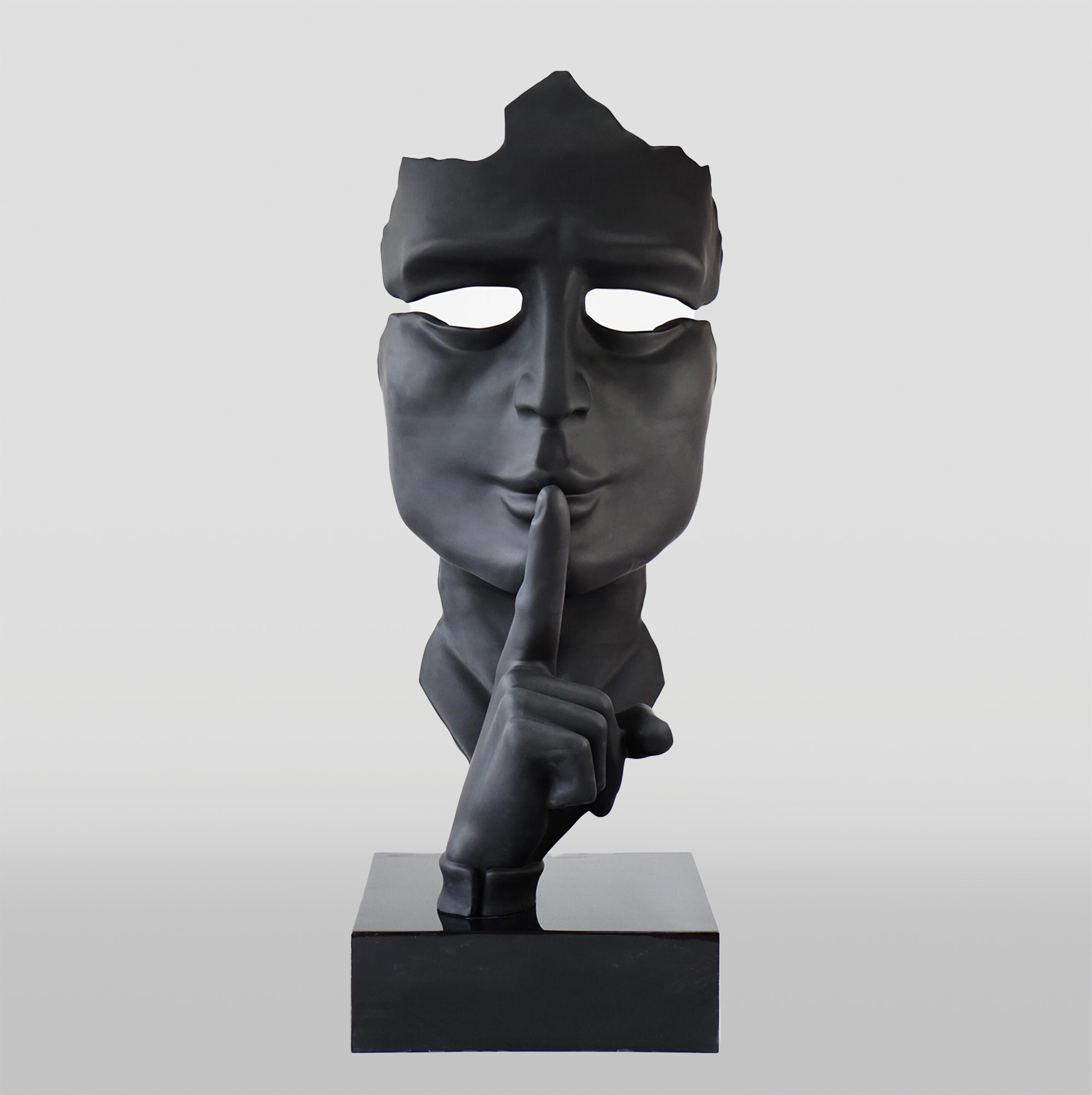 Black sculpture of a face with a broken top, hollow eyes, and a finger on the lips in a shushing gesture, mounted on a rectangular base.