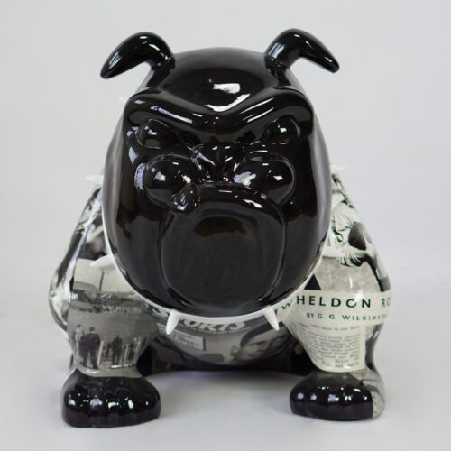 Ceramic bulldog statue with a glossy black head and newspaper print on its body.