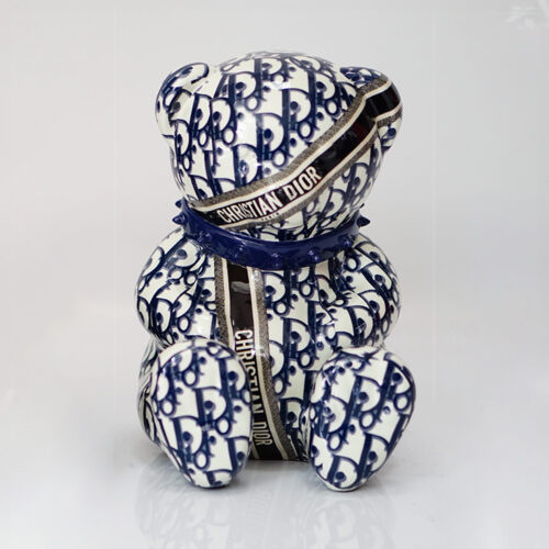 A ceramic bear figurine with a blue and white pattern, featuring the text 