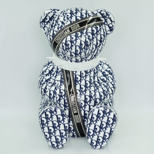 A Christian Dior pattern-covered teddy bear with a black ribbon bearing the text