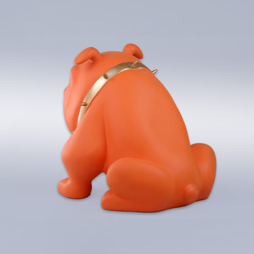 Orange bulldog sculpture with a gold spiked collar, facing away from the viewer, against a plain background.