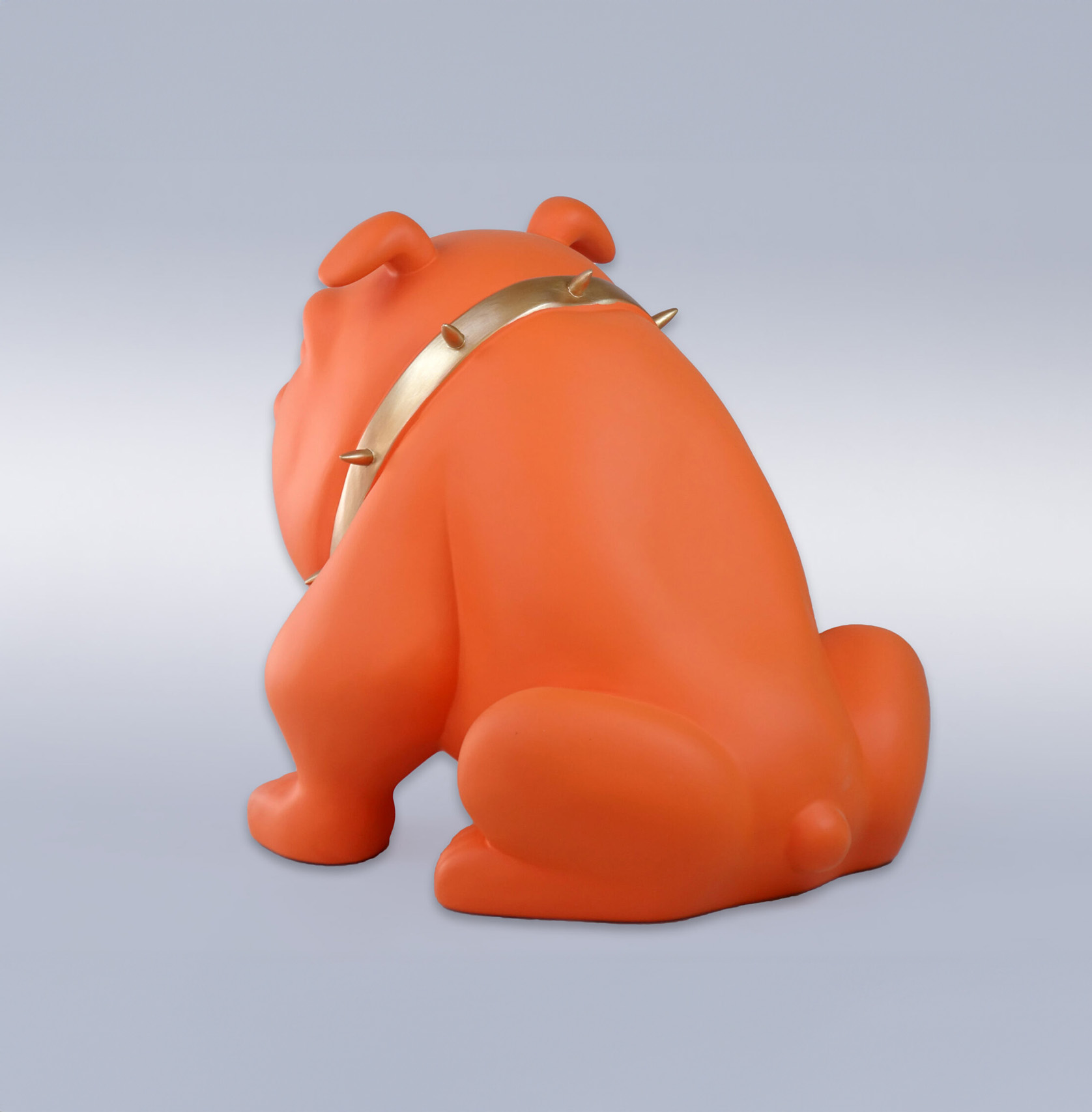 Bulldog Avella dog 22cm - orange mat 2 Orange bulldog sculpture with a gold spiked collar, facing away from the viewer, against a plain background.
