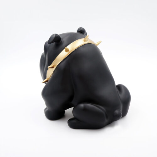 Black bulldog figurine with a gold spiked collar, facing away.