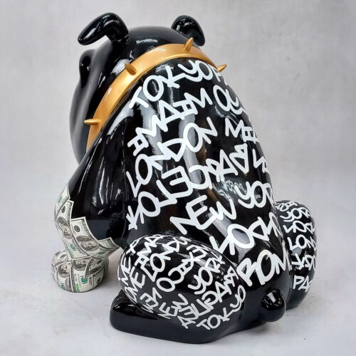 Black bulldog sculpture with white graffiti-like text of major city names (Tokyo, London, New York) wearing a gold spiked collar and dollar bill patterns on legs.