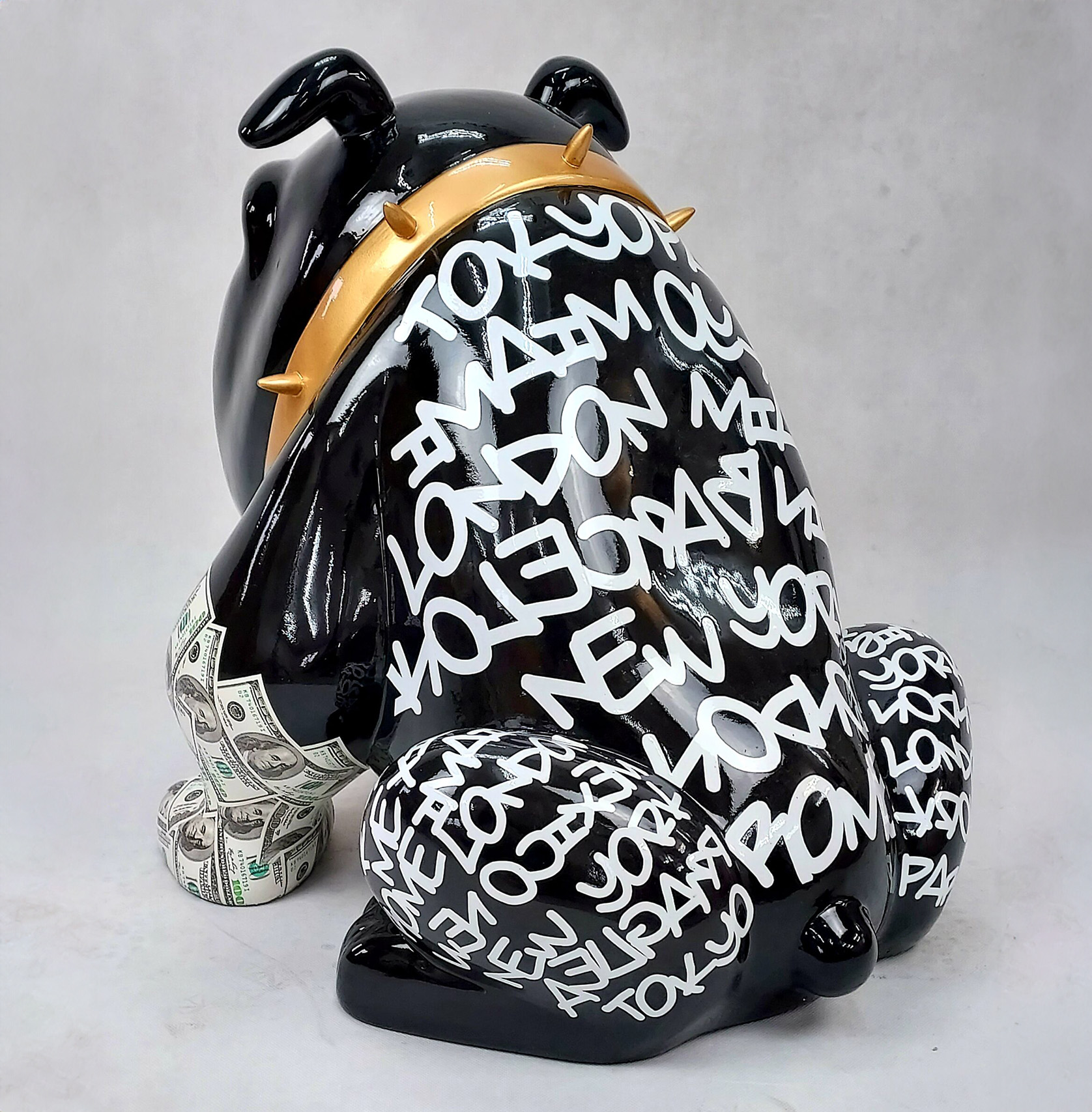 Bulldog Avella 55cm dog - Louis Paris 2 Black bulldog sculpture with white graffiti-like text of major city names (Tokyo, London, New York) wearing a gold spiked collar and dollar bill patterns on legs.