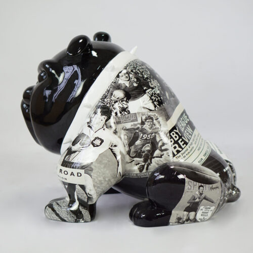 Black ceramic bulldog sculpture adorned with black and white sports images and newspaper clippings.