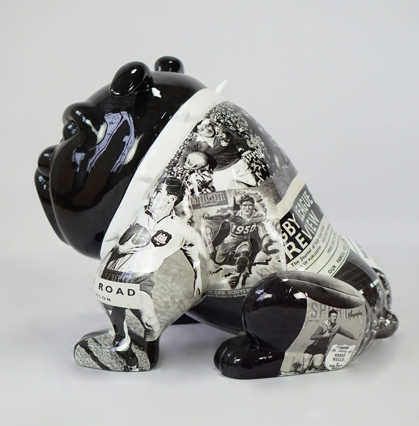 Bulldog Avella Dog 55cm - rugby 2 Black ceramic bulldog sculpture adorned with black and white sports images and newspaper clippings.