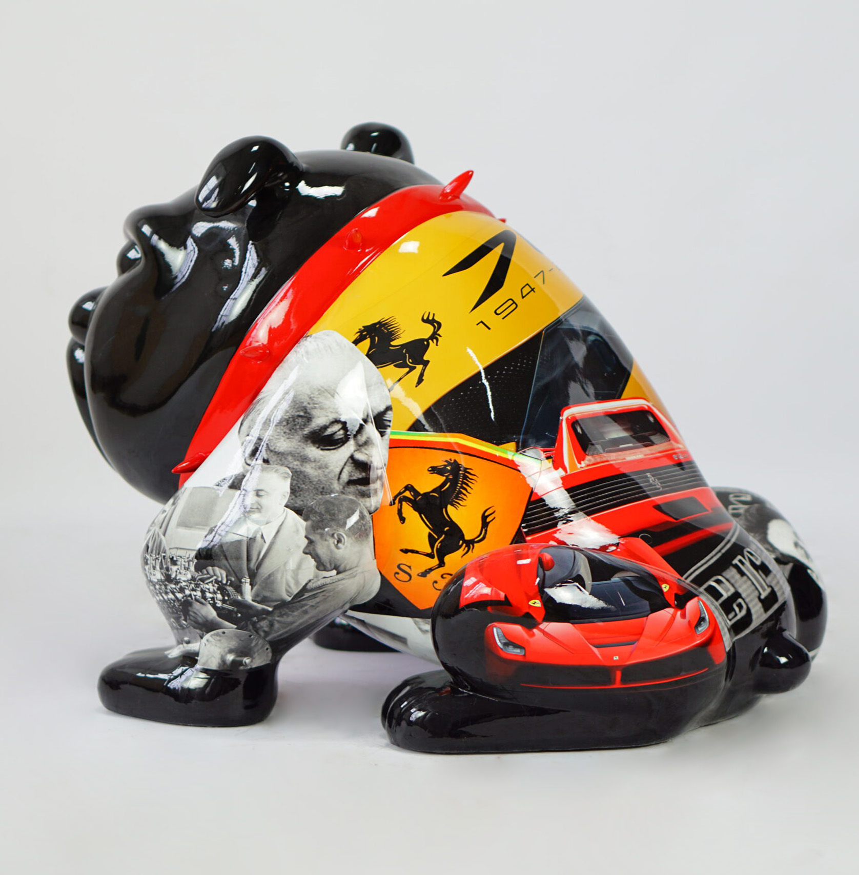 Bulldog Avella 55cm dog - Ferrari 2 A black bear sculpture decorated with Ferrari-themed imagery including the Ferrari logo, a red Ferrari car, and black-and-white photographs of individuals.
