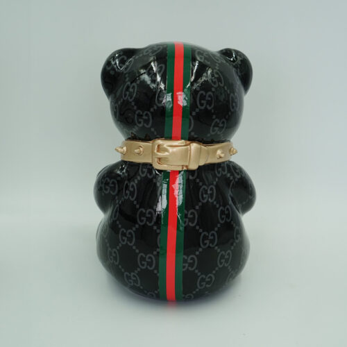 A shiny black bear figurine with a green and red striped pattern running vertically from head to base. The figurine is adorned with a gold belt around its neck and is decorated with a repeating 