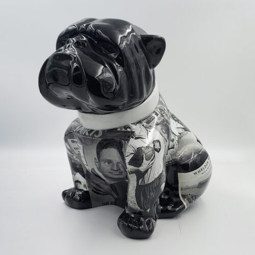 Ceramic dog statue with a glossy black head, white collar, and body covered in black and white newspaper clippings.