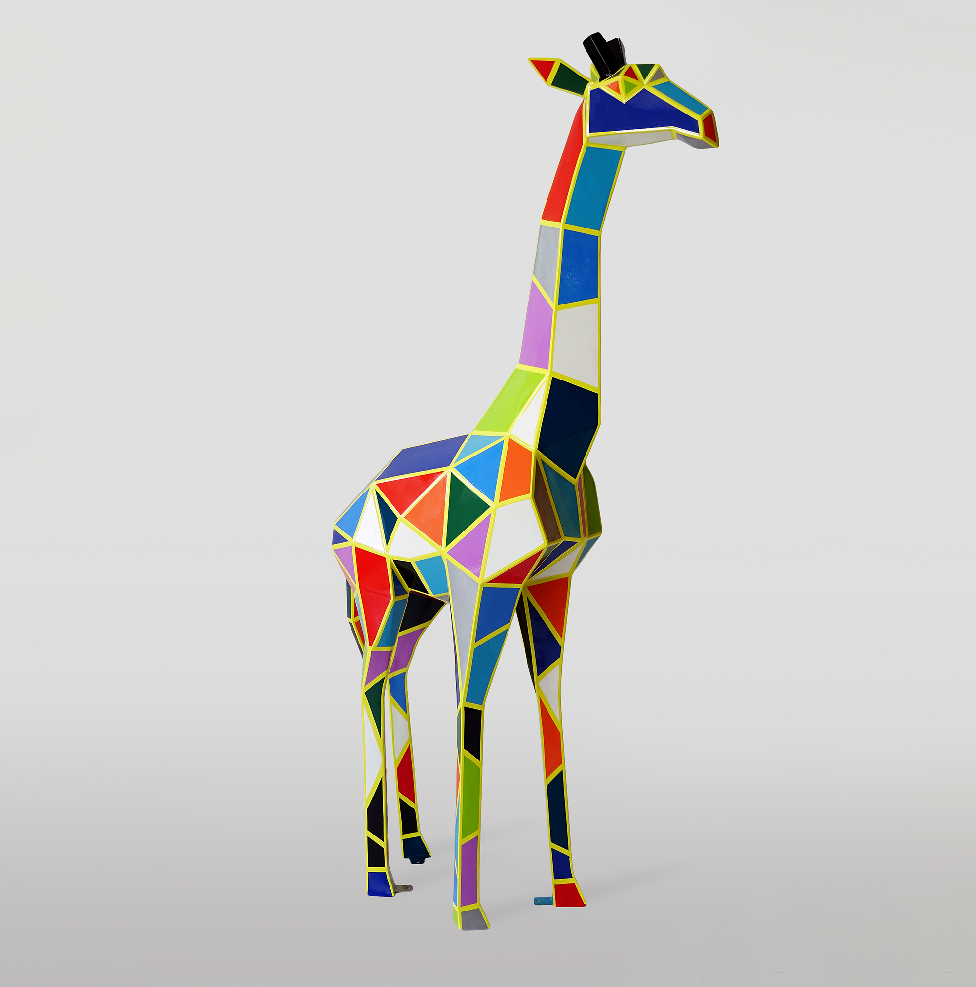A Large Geometric Giraffe Figure From Laminate - Arlecchino 1 Colorful, geometric giraffe sculpture with a patchwork design on a plain background.