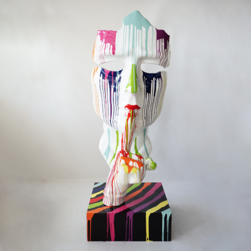 Colorful sculpture of a stylized human face with finger to lips, dripping with paint, on a multicolored striped base.