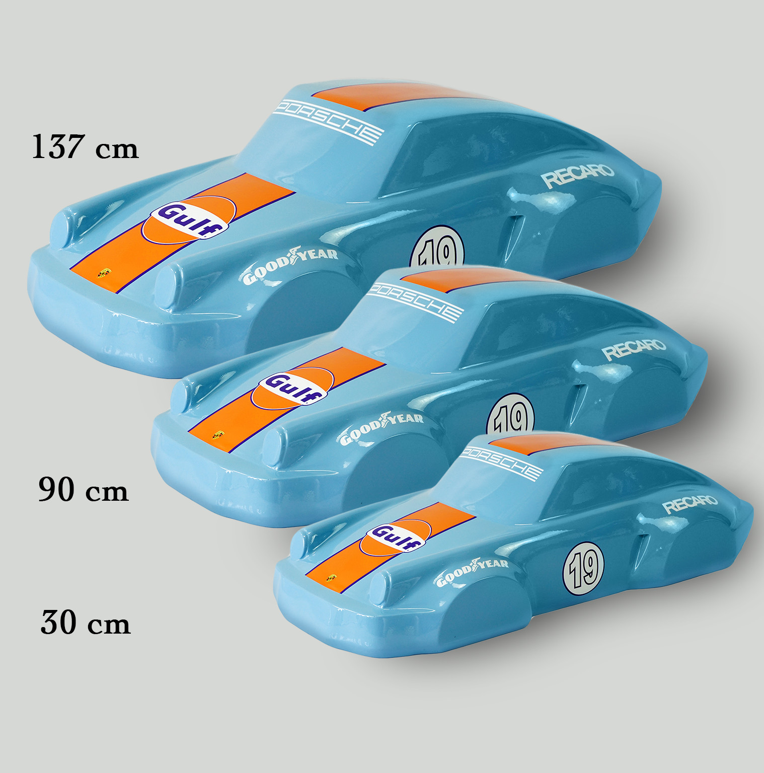 Car model 911 - Motif 19 2 Three blue model cars with Gulf and Goodyear branding in different sizes (137 cm, 90 cm, and 30 cm) arranged in a descending order.