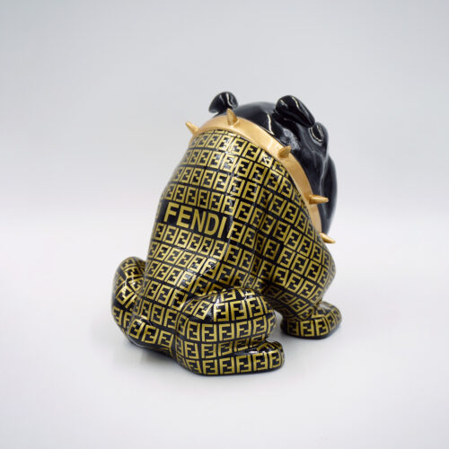Ceramic dog figurine with black and gold Fendi logo pattern wearing a gold spiked collar.