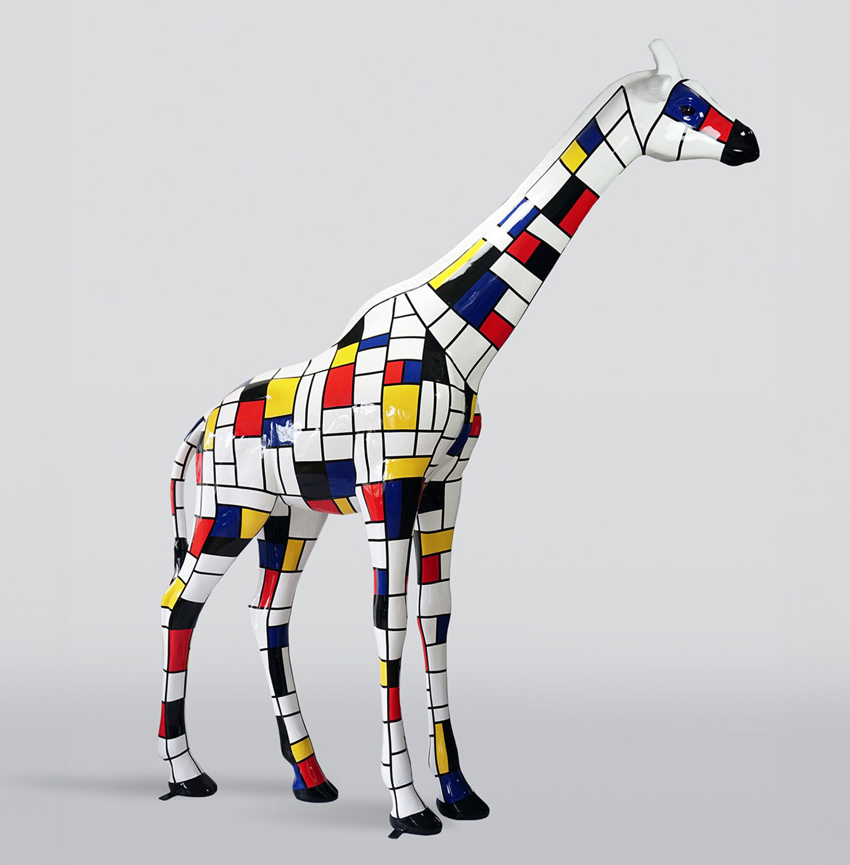 Large life-sized giraffe figure - Mondrian 1 Rzeźba żyrafy w stylu Mondriana, pokryta kolorowymi prostokątami w kolorach białym, czarnym, czerwonym, żółtym i niebieskim.
