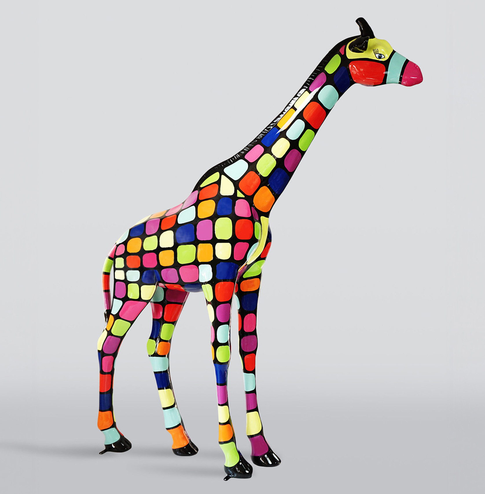 A large life-size giraffe figure - Smartie 1 Kolorowa figurka żyrafy z wzorem w kwadraty w różnych kolorach.