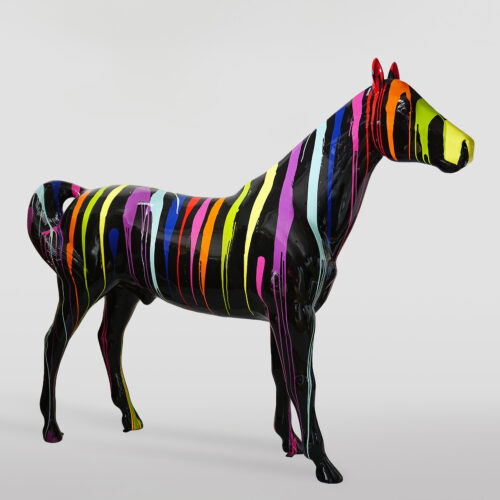 Czarna rzeźba konia pokryta pionowymi, kolorowymi smugami farb w odcieniach żółci, zieleni, czerwieni, niebieskiego, fioletu i różu.