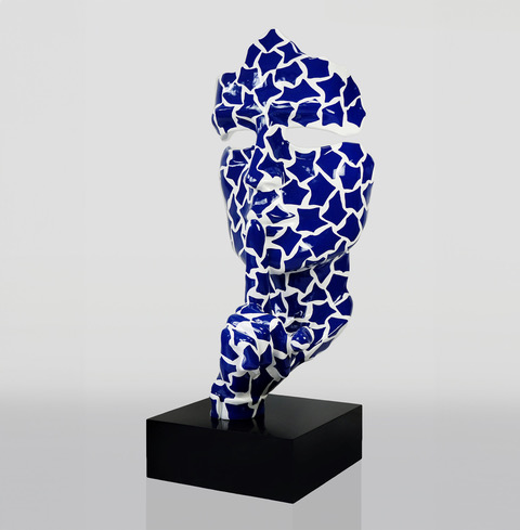 Rzeźba przedstawiająca twarz z dłońmi, pokryta wzorem w niebiesko-białe gwiazdy, umieszczona na czarnym postumencie.