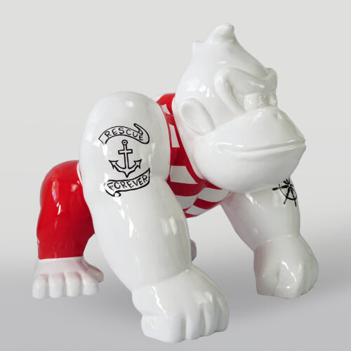 Ceramic sculpture of a gorilla in a crouching pose with red and white stripes on its body and black tattoo designs on its arms.