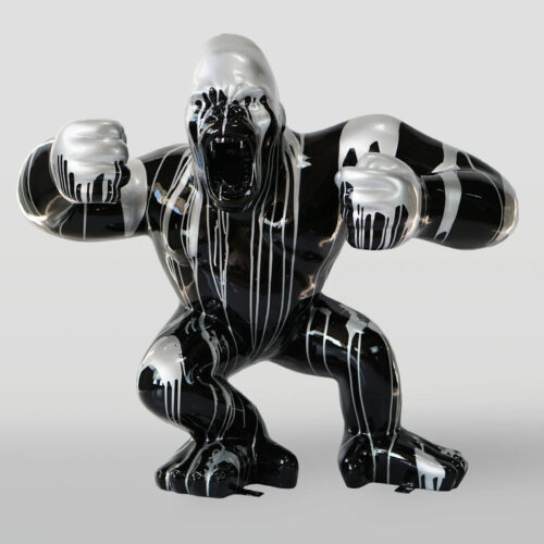 Czarna figurka goryla, pokryta białymi i srebrnymi smugami farby, stojąca w agresywnej pozycji.