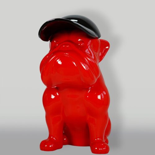Red bulldog figurine wearing a black cap.