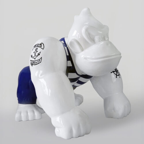 White ceramic gorilla figure with navy blue pants and striped shirt, featuring nautical tattoos on its arms.