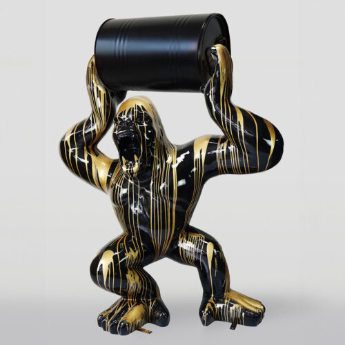 Sculpture of a black and gold gorilla holding a black barrel above its head.